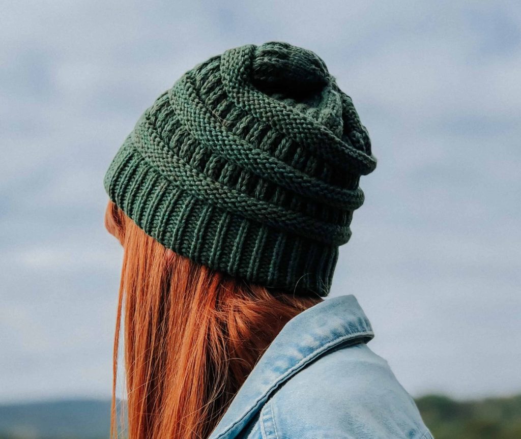 A photo of a girl with red hair wearing a green hat