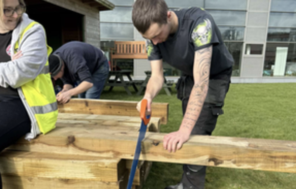 Finlay Thomson sawing some wood for new planters in the wellbeing space.